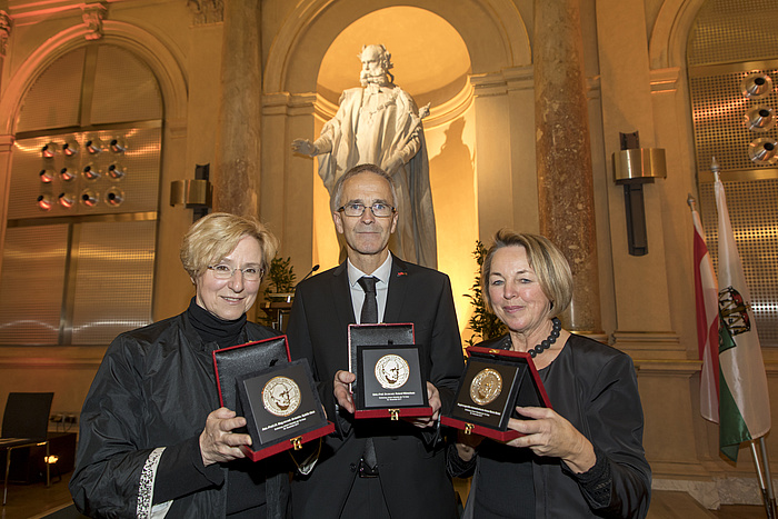 Von links nach rechts: Sybille Mick, Roland Würschum und Anna Maria Moisi zeigen stolz ihre Erzherzog-Johann-Medaillen in der Aula der TU Graz.