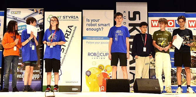 Seven young people stand on a stage.