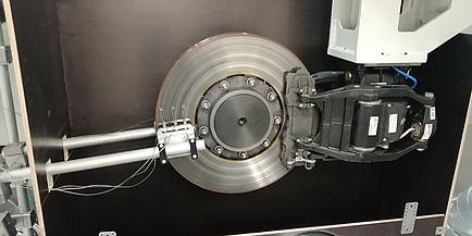 The brake disc of a train is mounted in a test stand. Sensors are located on the left and right of the brake disc.