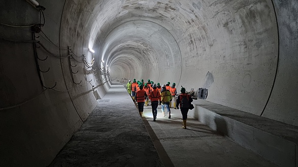 Eine Gruppe von Menschen geht von der Kamera weg durch eine Tunnelröhre.