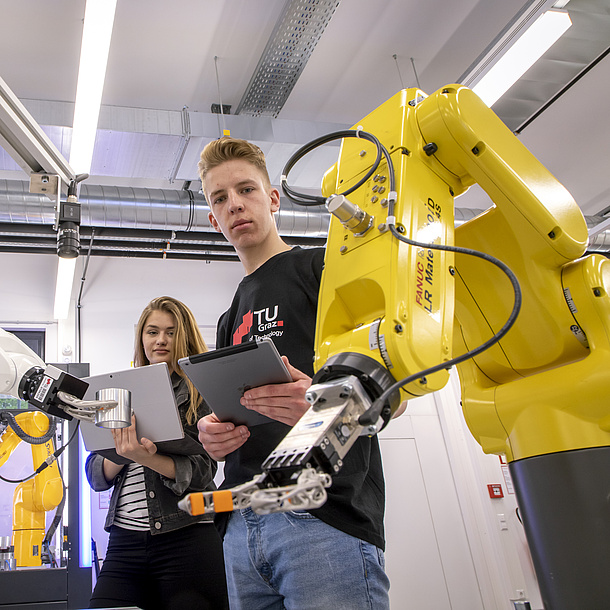 Studierende des Bachelorstudiums Digital Engineering der TU Graz hinter einem Roboterarm.