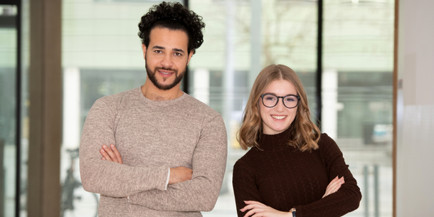 Zwei Studierende blicken  in die Kamera.