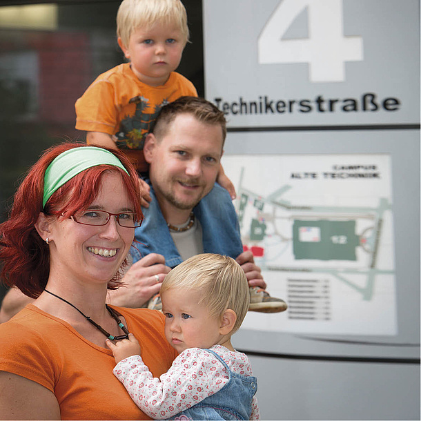 Couple with two children standing in front of an information board. Photo source: Lunghammer - TU Graz.