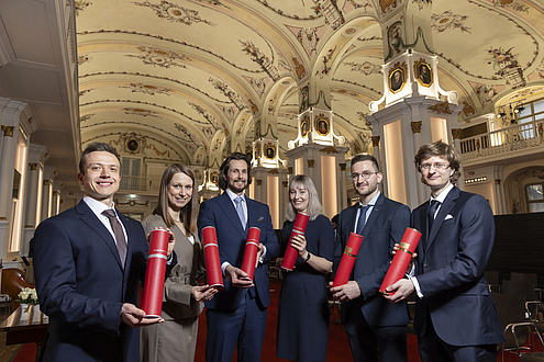 Six people smile at the camera. They are festively dressed.