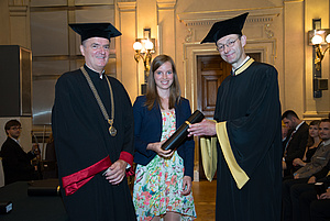 Dean and Dean of handing over the degree to the happy female candidate in the middle