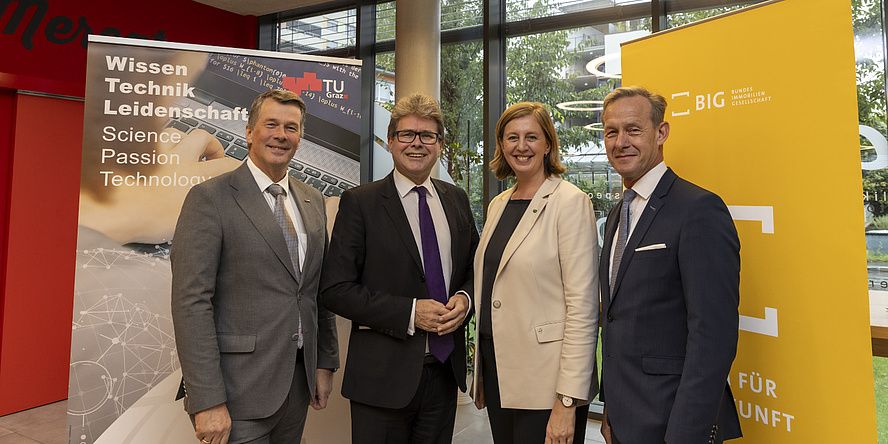 Four people, three men and one woman, smile into the camera.