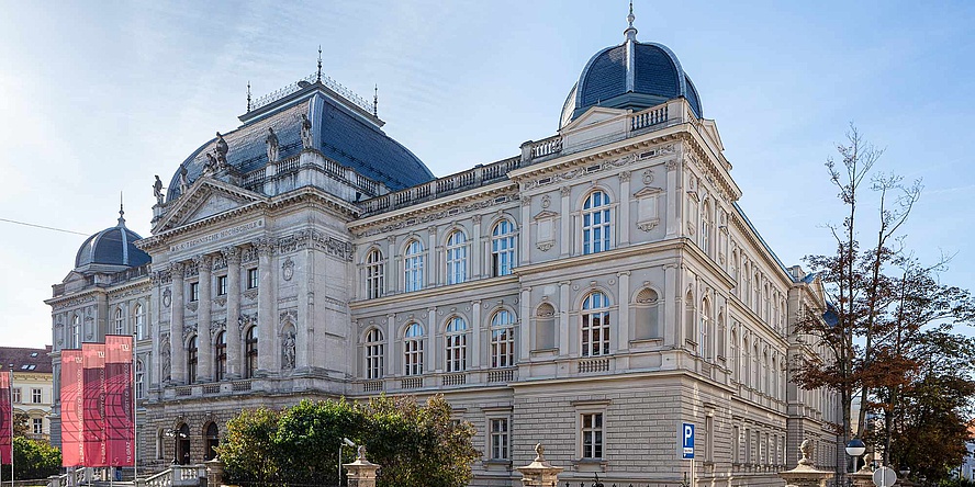 Ein großes altes Gebäude mit mehreren Stockwerken mit Kuppeln und Statuen ist auf dem Bild zu sehen. 