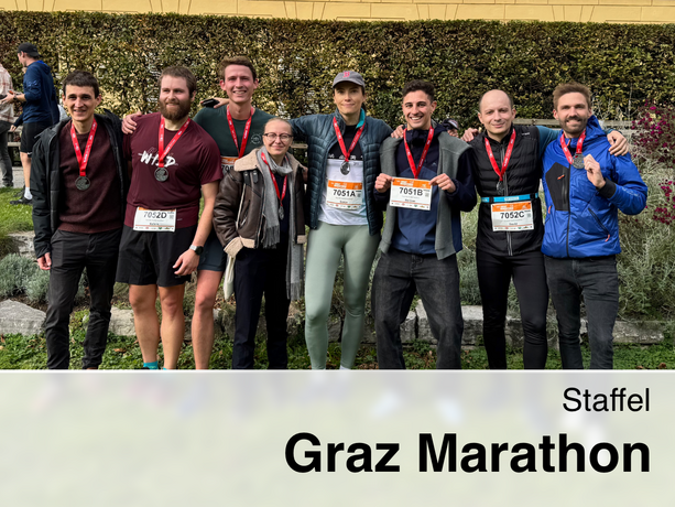 The image shows eight smiling participants from IEE standing in a row after the relay race at the Graz Marathon. They are proudly displaying their medals, which they are wearing around their necks.