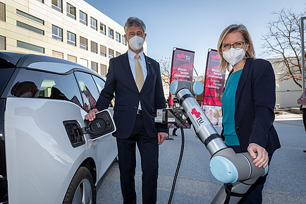 Man and woman next to an e-car with automatic e-charging robot