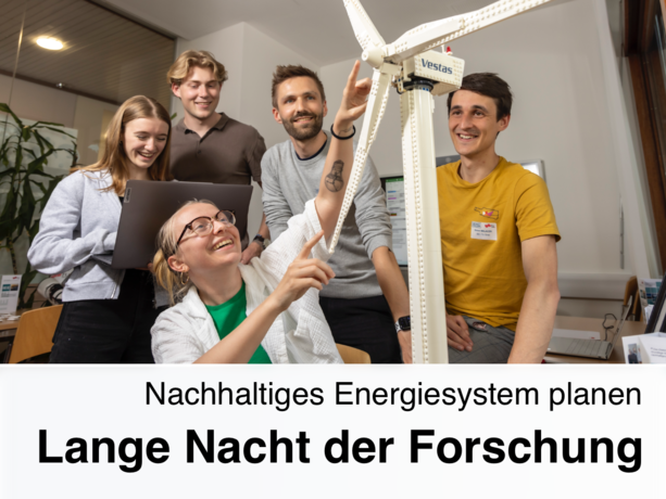 One person points to a miniature wind turbine and four people stand behind it and watch.
