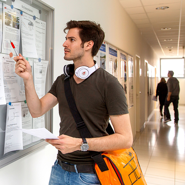 Young man standing in front of a board with information. Photo source: Lunghammer - TU Graz