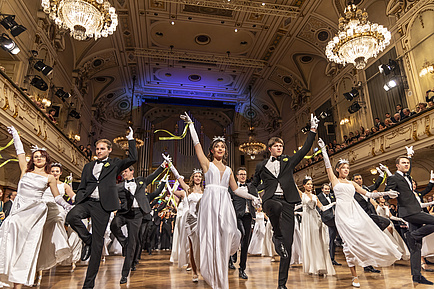 Männer und Frauen tanzen in einem Ballsaal.