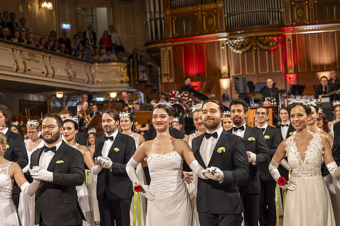 Männer und Frauen tanzen in einem Ballsaal.