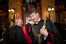 Two men in the picture: One man hangs a golden chain around the other man's neck - the rector's chain. Both are beaming.