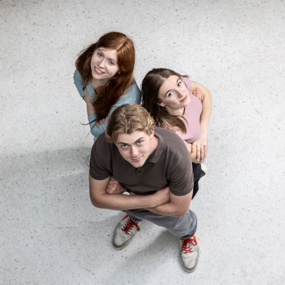 Gruppe von drei Personen stehend; Aufnahme von oben; Personen schauen noch oben