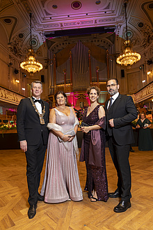 Zwei Frauen und zwei Männer in festlicher Kleidung stehen nebeneinander in einem Ballsaal.