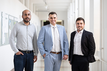 Three men smile into the camera.