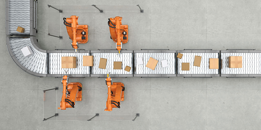 Vogelperspektive eines Förderbandes in einem Logistikzentrum. Roboterarme nehmen Pakete vom Förderband.