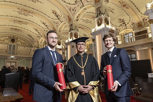 Three people smile at the camera. They are festively dressed.