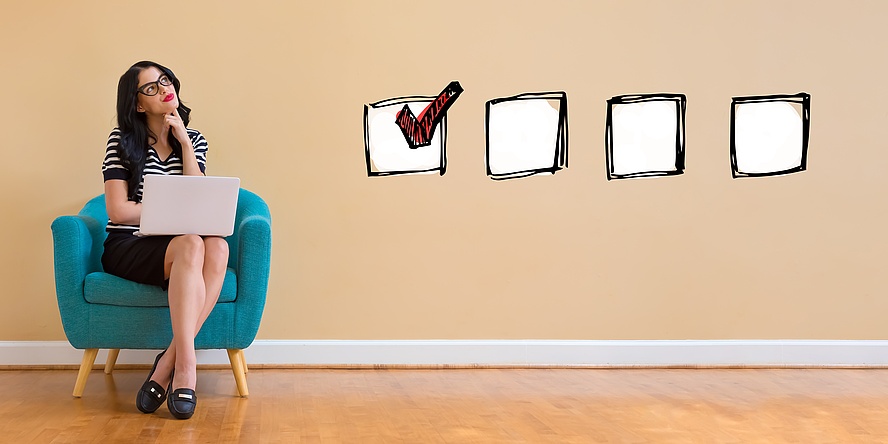 Young woman with a laptop is sitting in an armchair in a thoughtful pose.   Next to her, 4 squares are depicted graphically, one of which is marked with a tick.